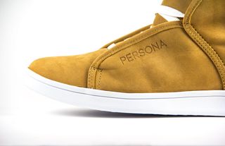 白色表面上未配对的棕色和白色 Persona 绒面革运动鞋