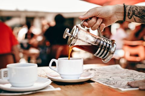 在白色陶瓷杯上倒咖啡的人 在白色陶瓷杯上倒咖啡的人