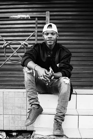 坐在卷帘门附近窗台上的男子