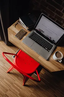 Creatives办公桌，砖墙前有笔记本电脑、相机、日记和书籍