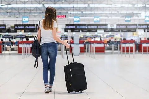 机场带行李的年轻女子的后视图 机场带行李的年轻女子的后视图