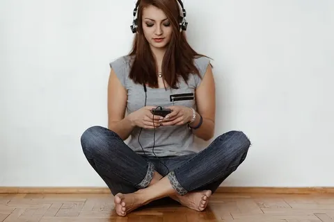 戴着耳机听音乐的美丽年轻女子 戴着耳机听音乐的美丽年轻女子