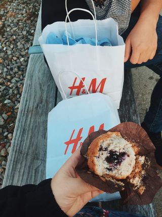 在H&m的两个白色纸袋附近拿着松饼的人