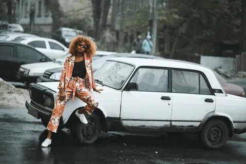 身穿黑色衬衫和棕色开衫的女子坐在白色轿车上