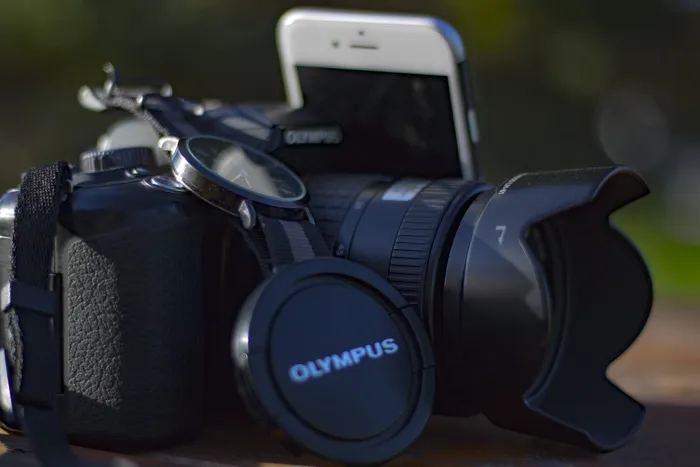 银色Iphone 6旁边的黑色Olympus单反相机