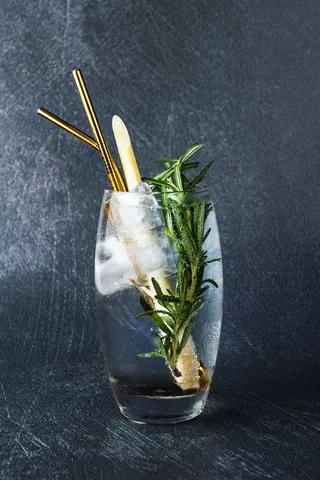 迷迭香药草装在透明的玻璃里，里面有水和黄色的稻草