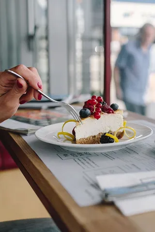 在自助餐厅享用奶酪蛋糕和水果咖啡的女士