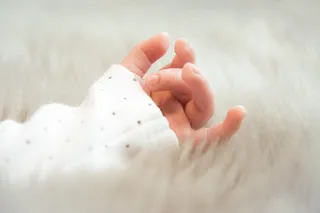 婴儿穿着白色袖子的左手照片