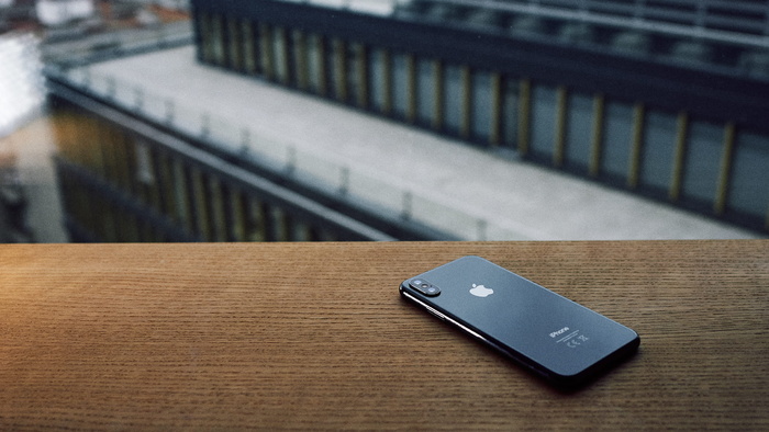 棕色木桌上太空灰色iPhone X的聚焦照片