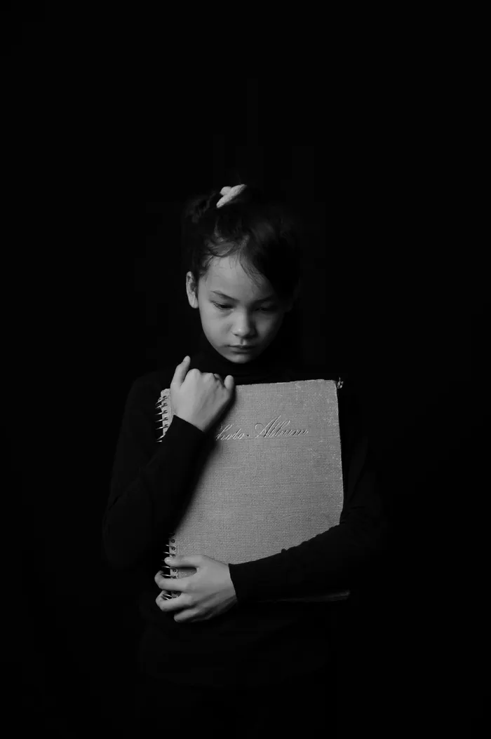 抱着灰色书的蹒跚学步的女孩
