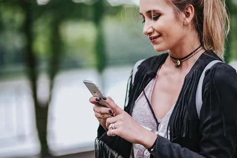 穿着黑色夹克和绿色扶手撕破牛仔裤的金发女人 穿着黑色夹克和绿色扶手撕破牛仔裤的金发女人
