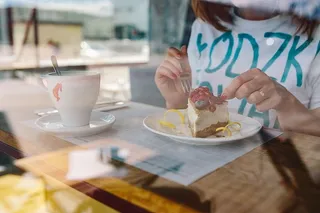 在自助餐厅享用奶酪蛋糕和水果咖啡的女士