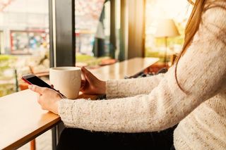 小女孩在咖啡馆用她的智能手机