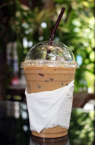 在热带花园的桌子上喝一杯冰咖啡