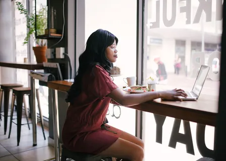 穿着红色连衣裙的女士在桌上使用笔记本电脑 穿着红色连衣裙的女士在桌上使用笔记本电脑