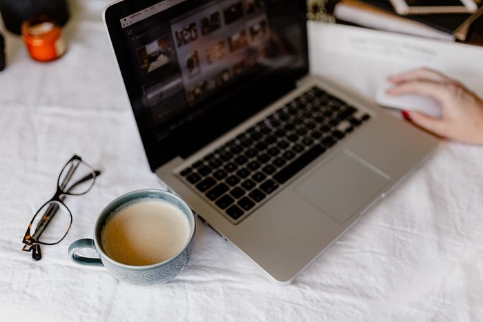 一位女士在一张桌子旁工作，桌上有一台笔记本电脑和一杯咖啡