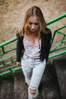 穿着黑色夹克和绿色扶手撕破牛仔裤的金发女人 穿着黑色夹克和绿色扶手撕破牛仔裤的金发女人