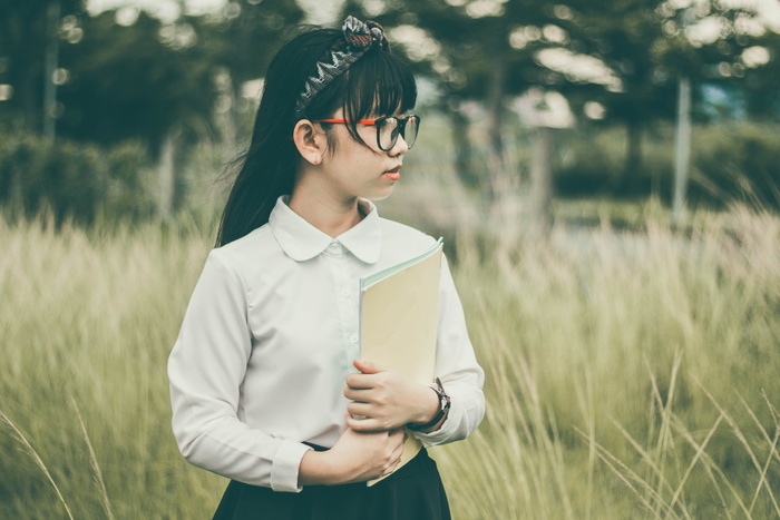 穿着白色长袖衬衫和黑色底裤的女孩拿着一个棕色文件夹