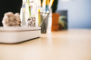 苹果无线路由器顶部的智者微型雕像。使用Home Office Essentials模糊背景