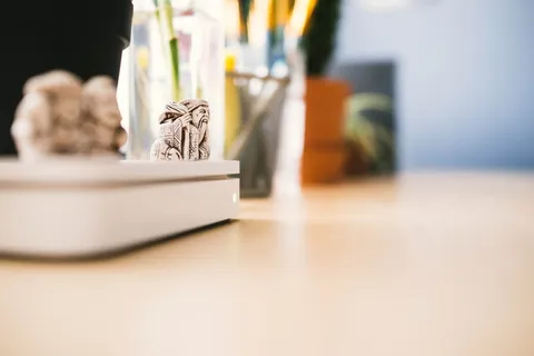 苹果无线路由器顶部的智者微型雕像。使用Home Office Essentials模糊背景 苹果无线路由器顶部的智者微型雕像。使用Home Office Essentials模糊背景