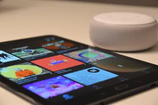 圆形白色便携式扬声器旁的黑色平板电脑