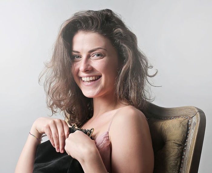 年轻女子坐在椅子上微笑着拿着一个包的肖像