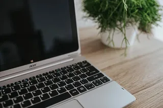 银色宏碁笔记本电脑放在一张木桌子上，上面有一株绿色植物、铅笔和一部苹果iPhone