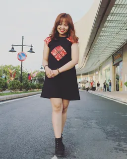 身穿黑色和红色帽子袖圆领连衣裙和黑色高帮运动鞋的女士 身穿黑色和红色帽子袖圆领连衣裙和黑色高帮运动鞋的女士