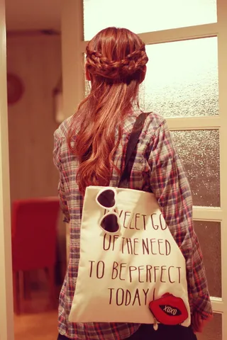 身穿灰色、蓝色和红色格子长袖衬衫和白色皮革肩包的女士