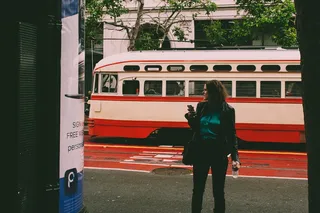 在红白相间的缆车旁穿着黑色外套的女子