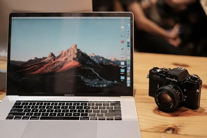 MacBook Pro，黑色美能达数码单反相机旁带触摸屏