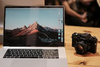 MacBook Pro，黑色美能达数码单反相机旁带触摸屏