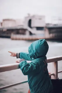 蹒跚学步的孩子穿着绿色连帽夹克,右手食指指向 蹒跚学步的孩子穿着绿色连帽夹克,右手食指指向
