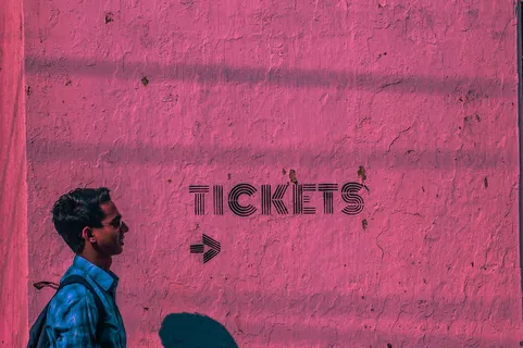 身穿蓝色运动衫和背包的男子穿过粉色墙壁