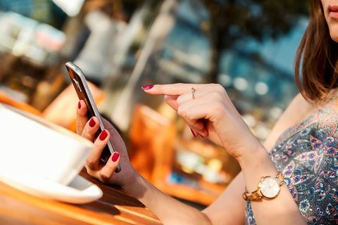 小女孩在餐厅花园里用智能手机打字