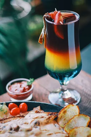 带有黑色、黄色和蓝色液体的透明短脚玻璃