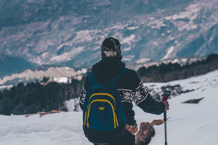 穿着黑白夹克和蓝色背包滑雪的男子