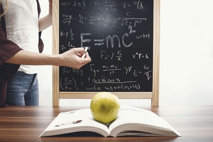 教师在黑板上教和写数学方程式。教育和学校理念。