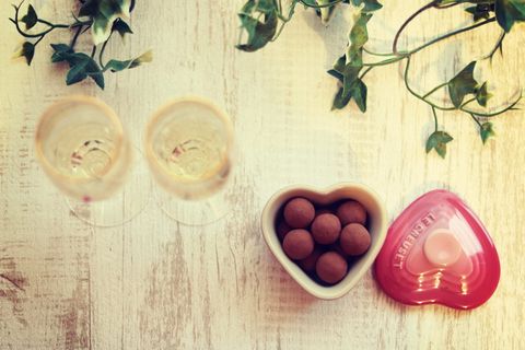 两个透明的长柄酒杯，在装满糕点的心形陶瓷容器旁边