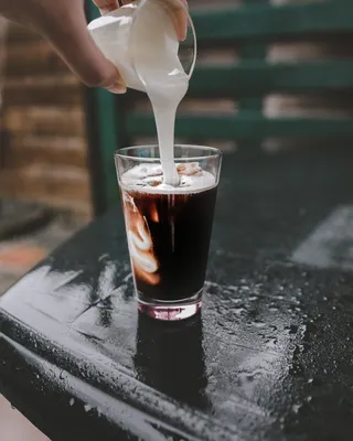 将白色液体倒在玻璃杯上的人