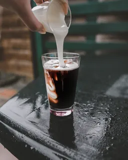 将白色液体倒在玻璃杯上的人 将白色液体倒在玻璃杯上的人