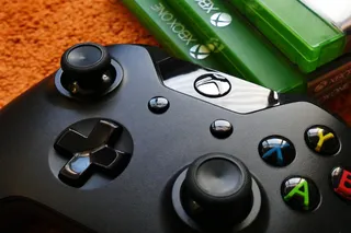 三个Xbox One机箱旁边的Xbox One控制器