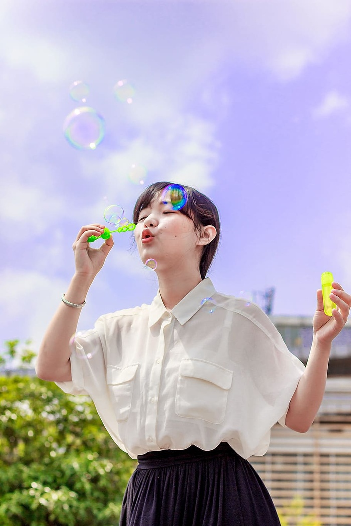 穿着白色上衣的女人玩泡泡的照片