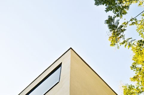 绿叶树旁的米色混凝土建筑