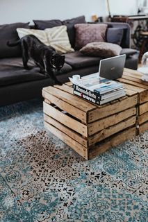 设计师设计的客厅内部有一张木箱桌和一块浅蓝色地毯