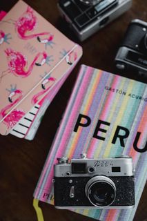 旧的模拟相机和粉红色的书放在木桌上