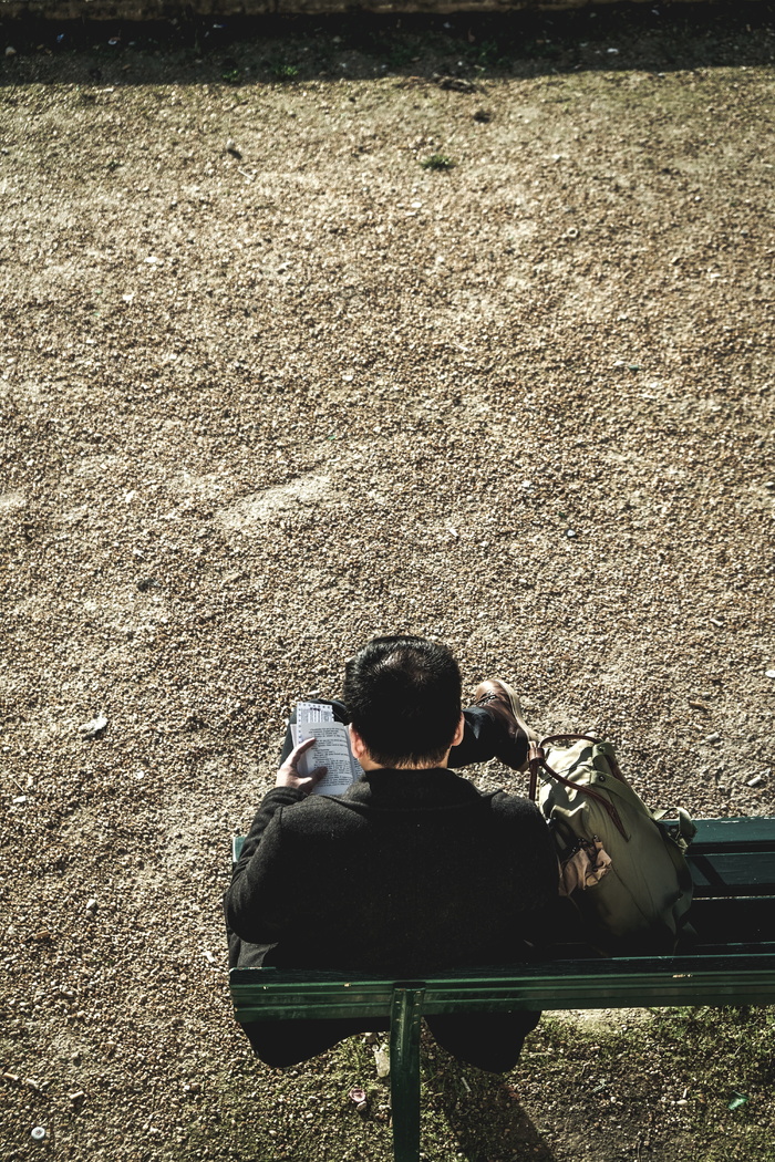 白天坐在室外绿色长椅上的男子