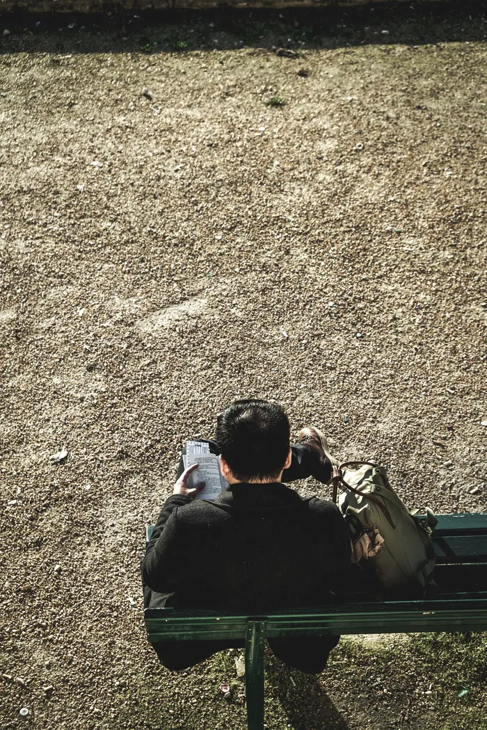 白天坐在室外绿色长椅上的男子