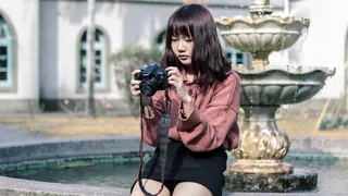 拿着相机的女人坐在喷泉旁