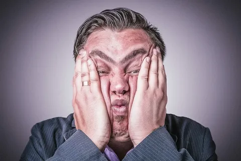 身穿灰色西装的男子举着脸的照片